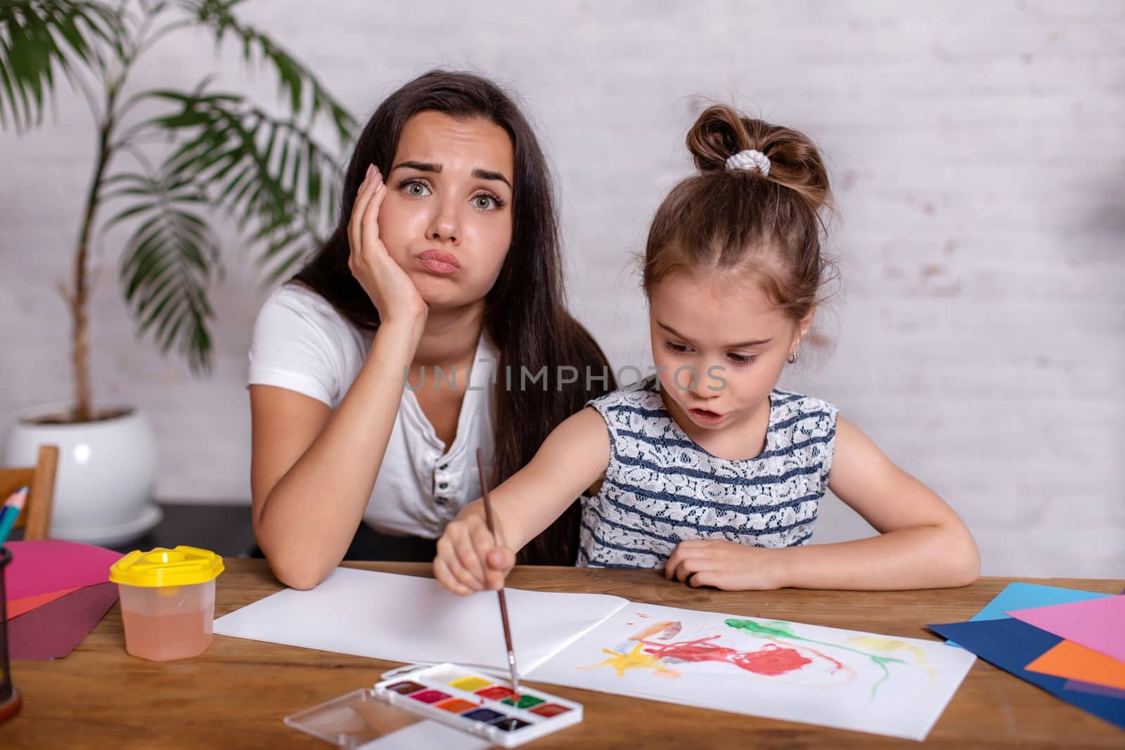 Happy family. Mother and daughter together paint. Woman helps the child girl.