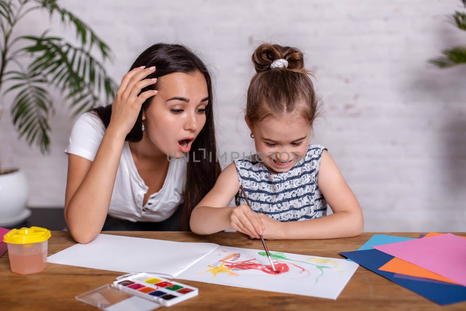 Happy family. Mother and daughter together paint. Woman helps the child girl.