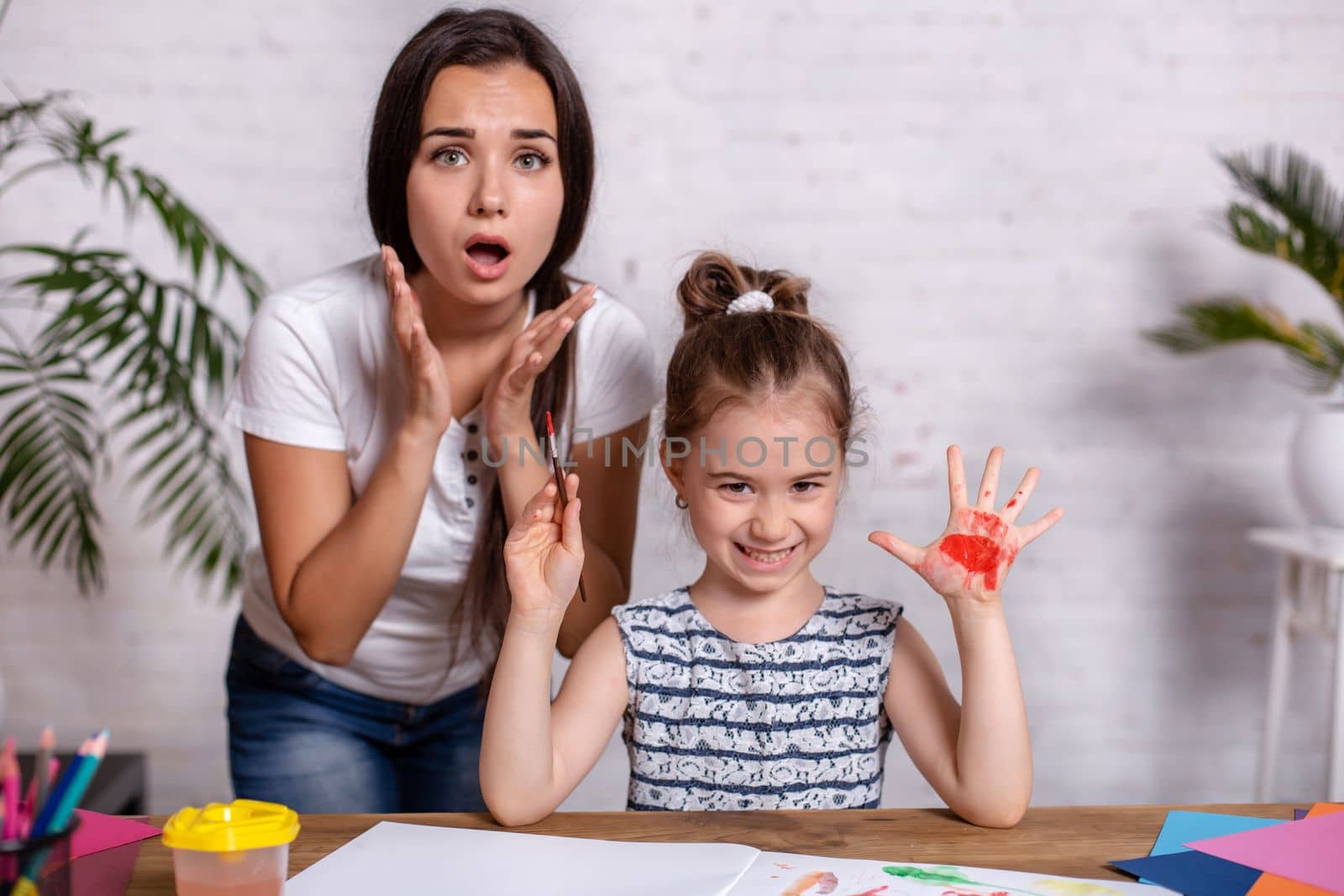 Happy family. Mother and daughter together paint. Woman helps the child girl.