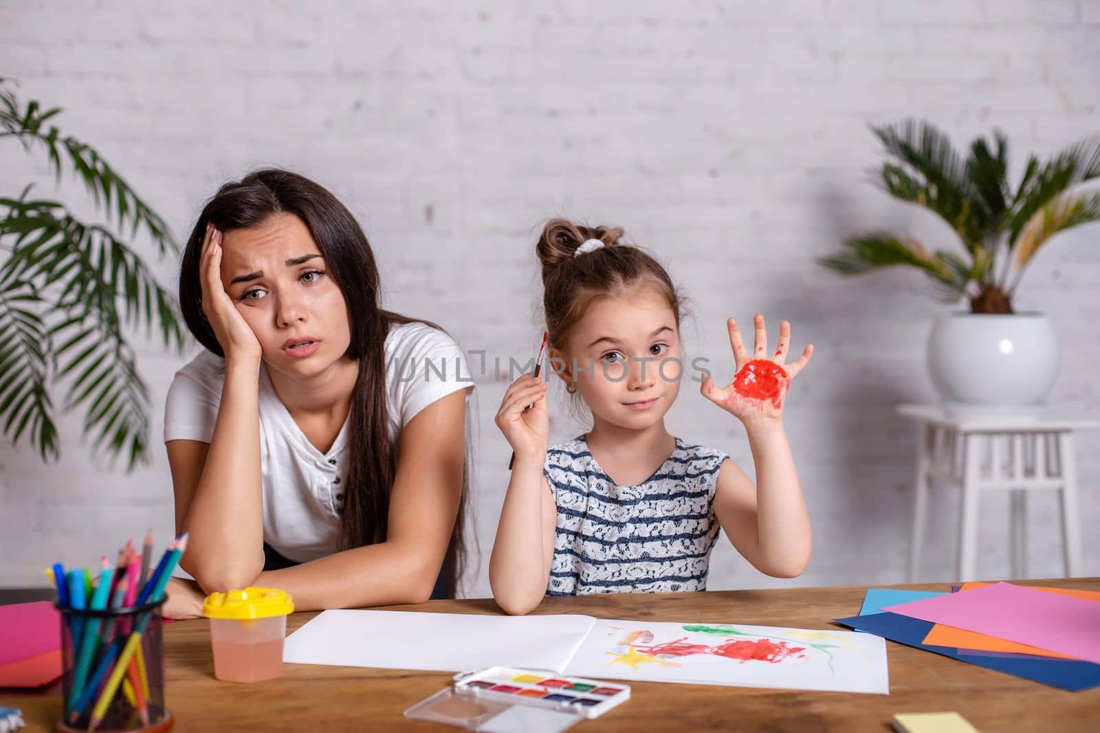 Happy family. Mother and daughter together paint. Woman helps the child girl.