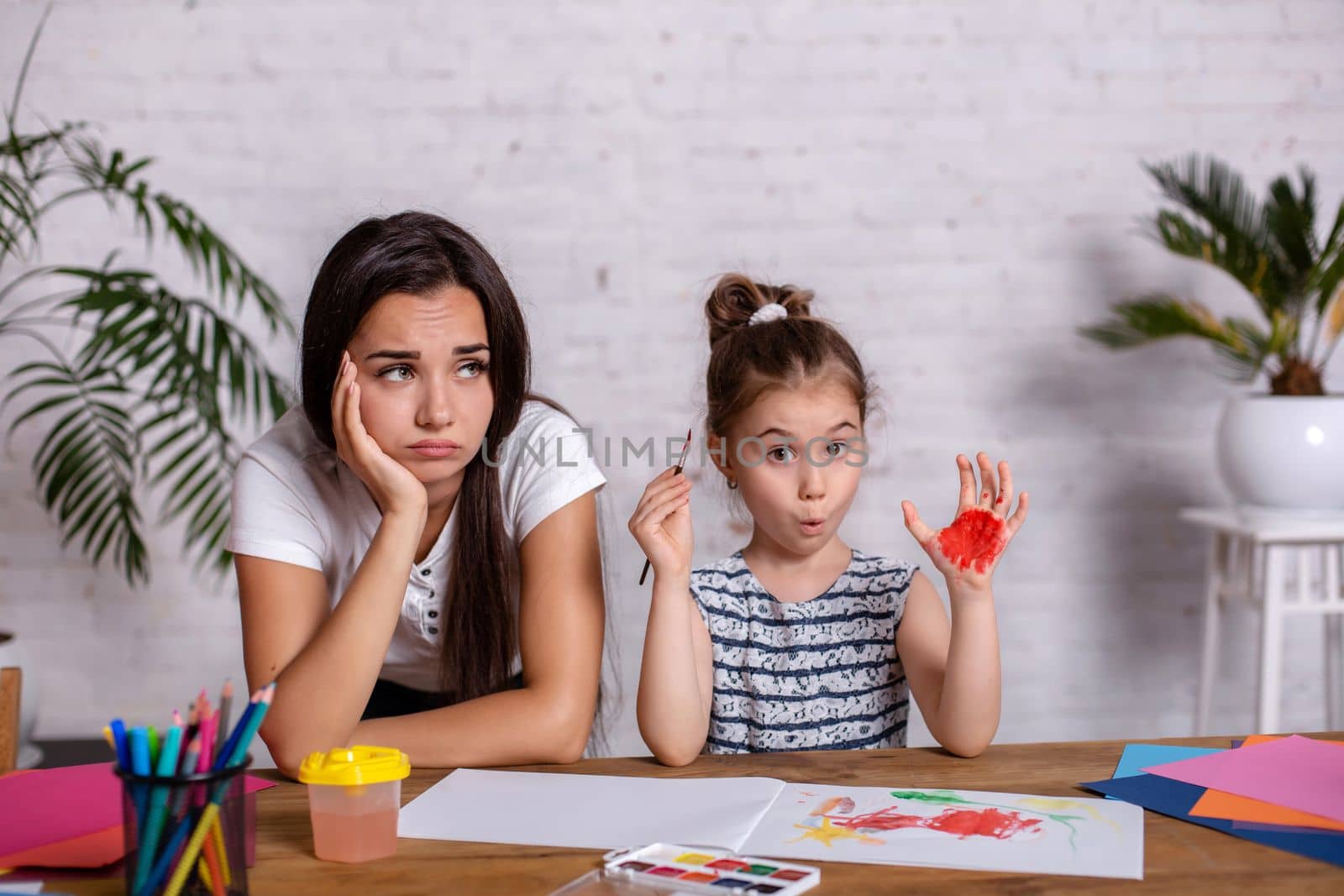 Happy family. Mother and daughter together paint. Woman helps the child girl.