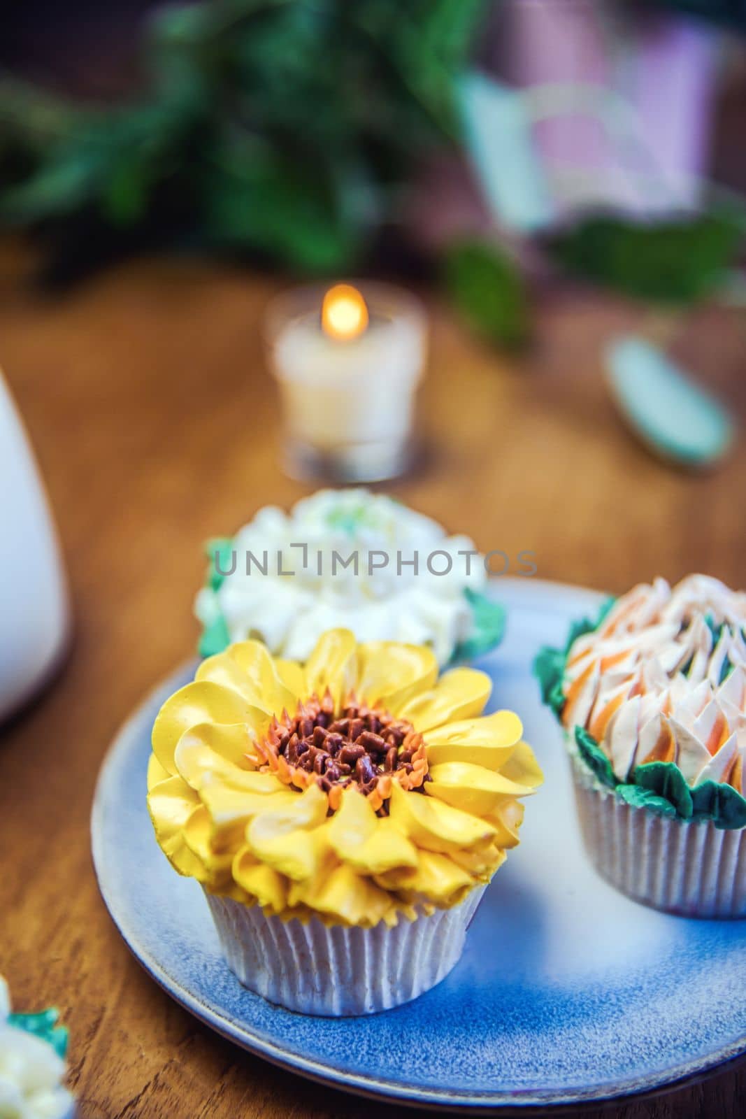 Various cupcakes decorated with colorful flower icing on wooden table, floral bouquet, wedding cake, High tea, Holiday concept Mothers day