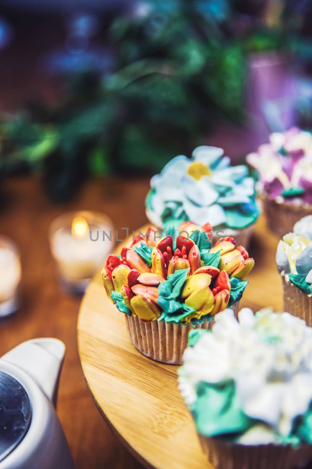 Various cupcakes decorated with colorful flower icing on wooden table, floral bouquet, wedding cake, High tea, Holiday concept Mothers day