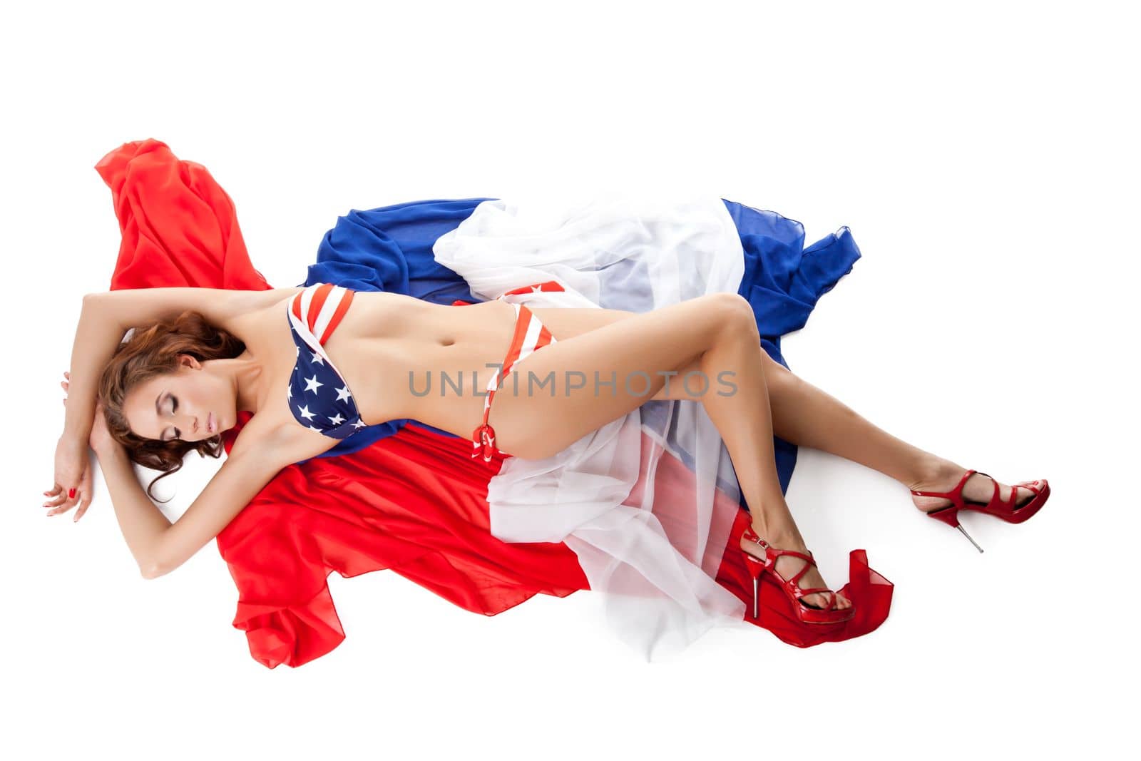 Smiling young woman in bikini lay on fabric isolated