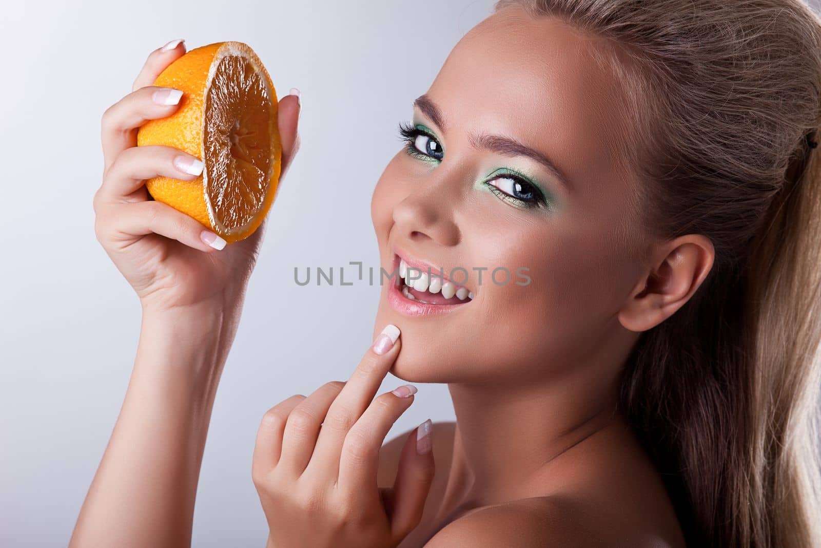 Beautiful young woman smile and squeeze orange