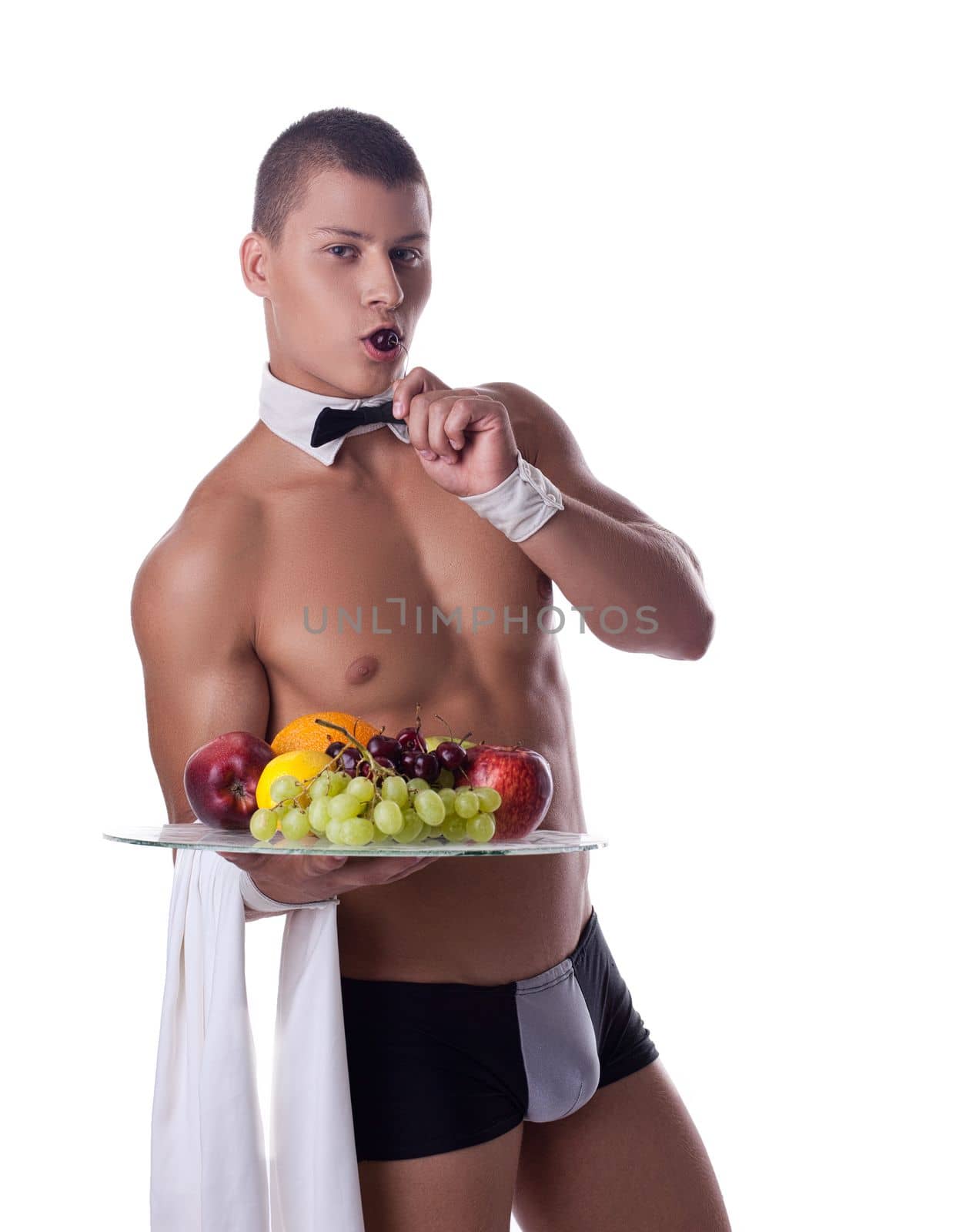 athletic man like striptease waiter hold fruits and eat cherry