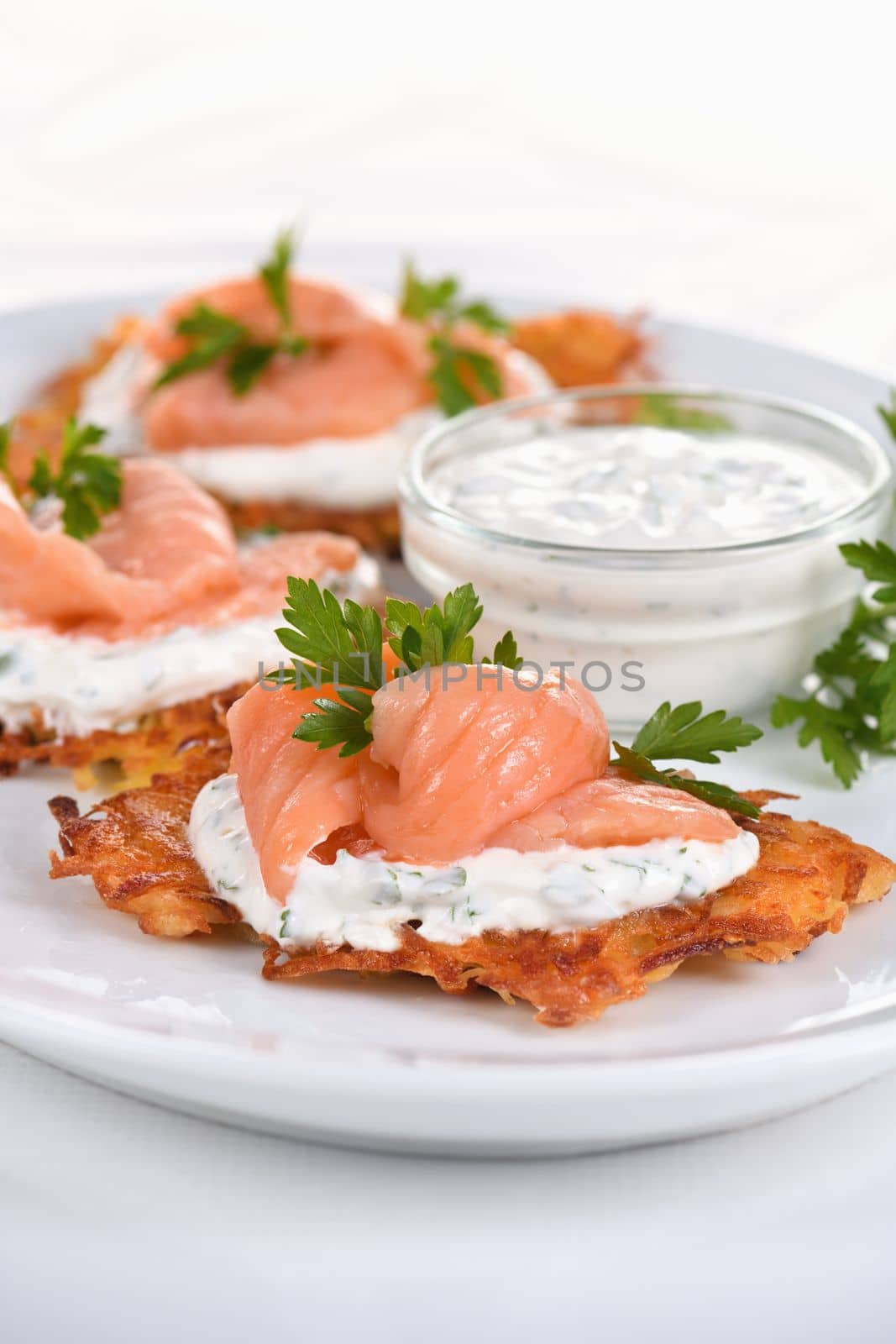 Crispy Potato fritters (a pancake, especially one made with grated potato) with cream cheese sauce with herbs and salmon