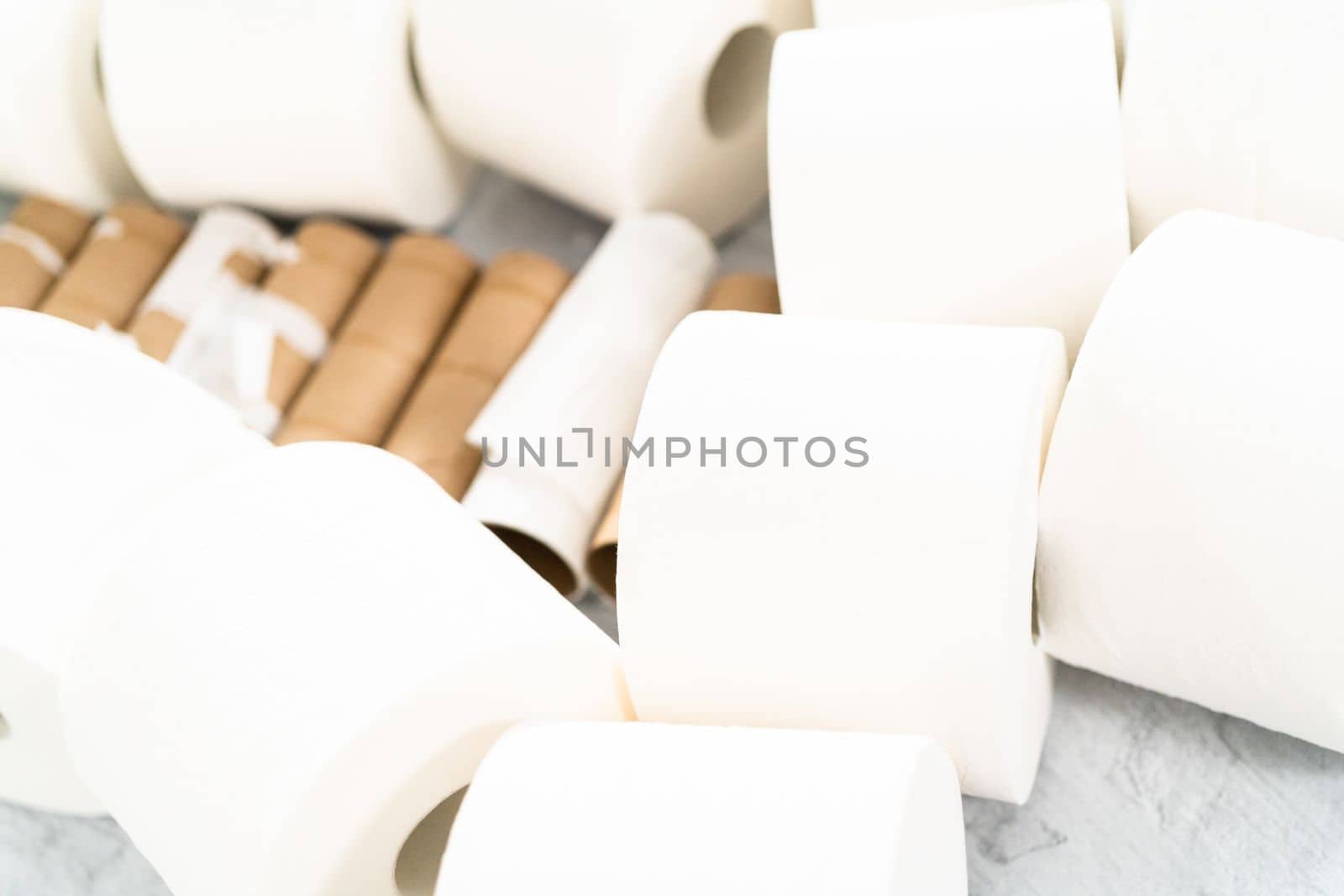 New and empty white toilet paper rolls on a gray background.