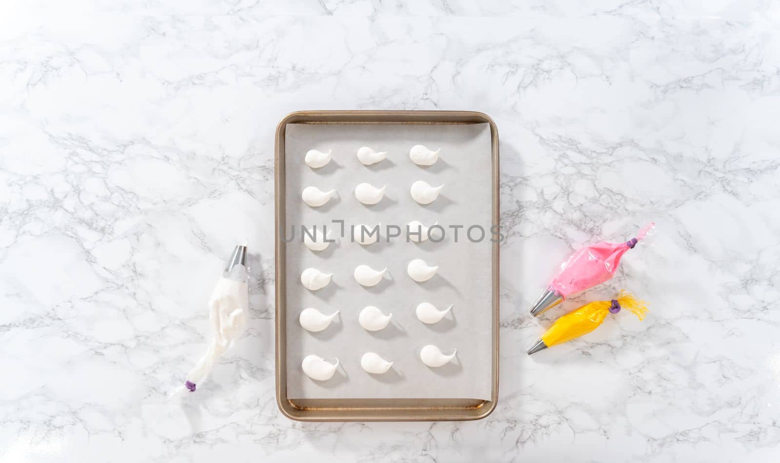 Piping meringue with piping bags into the baking sheet lined with parchment paper to bake Easter meringue cookies.