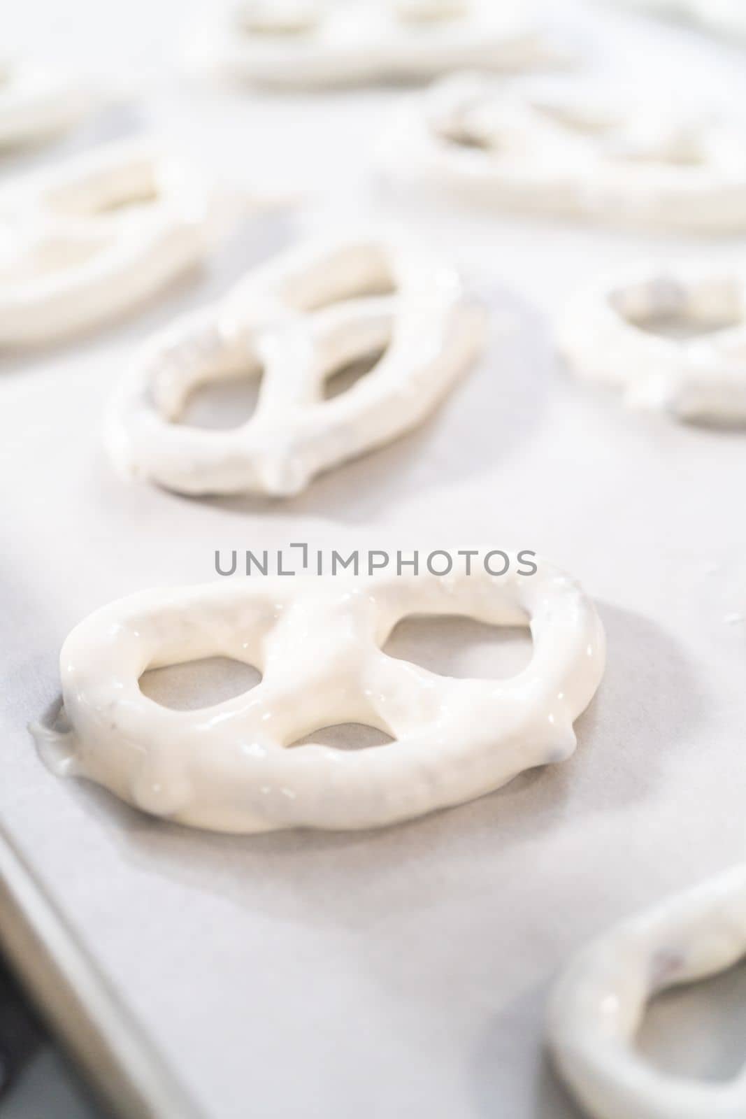 Dipping pretzels twists into melted chocolate to make chocolate-covered pretzel twists.