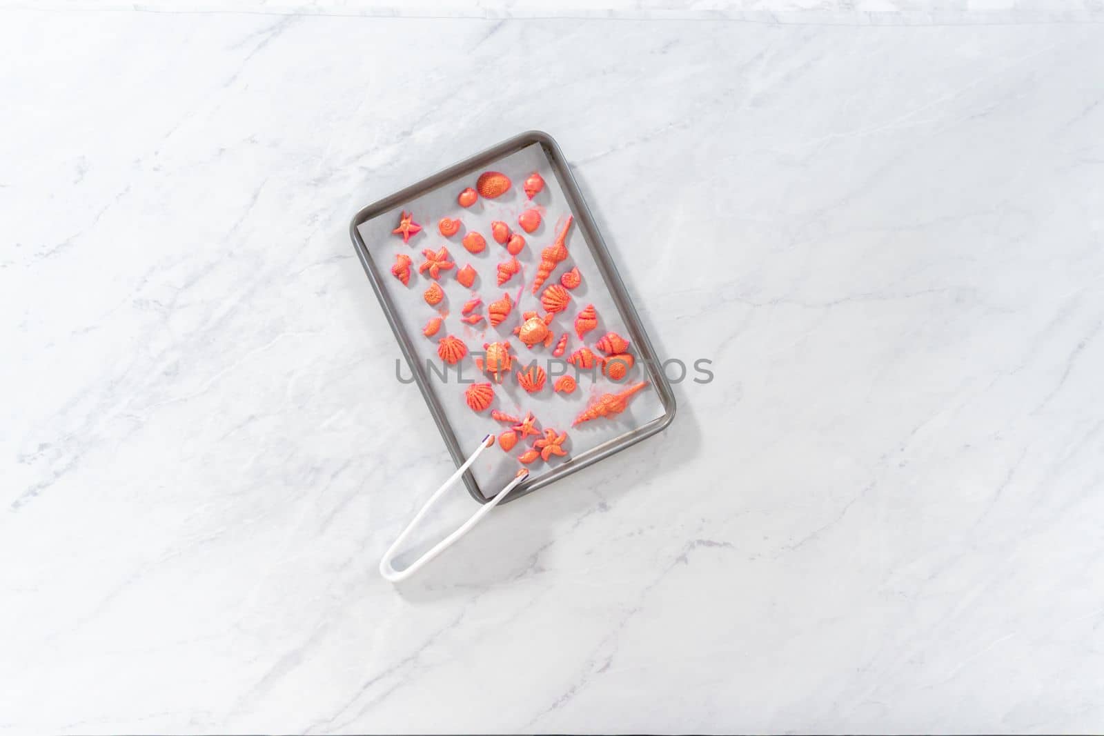 Flat lay. Painting sea-shaped chocolates with glittery luster to decorate chocolate-dipped pretzels twists.