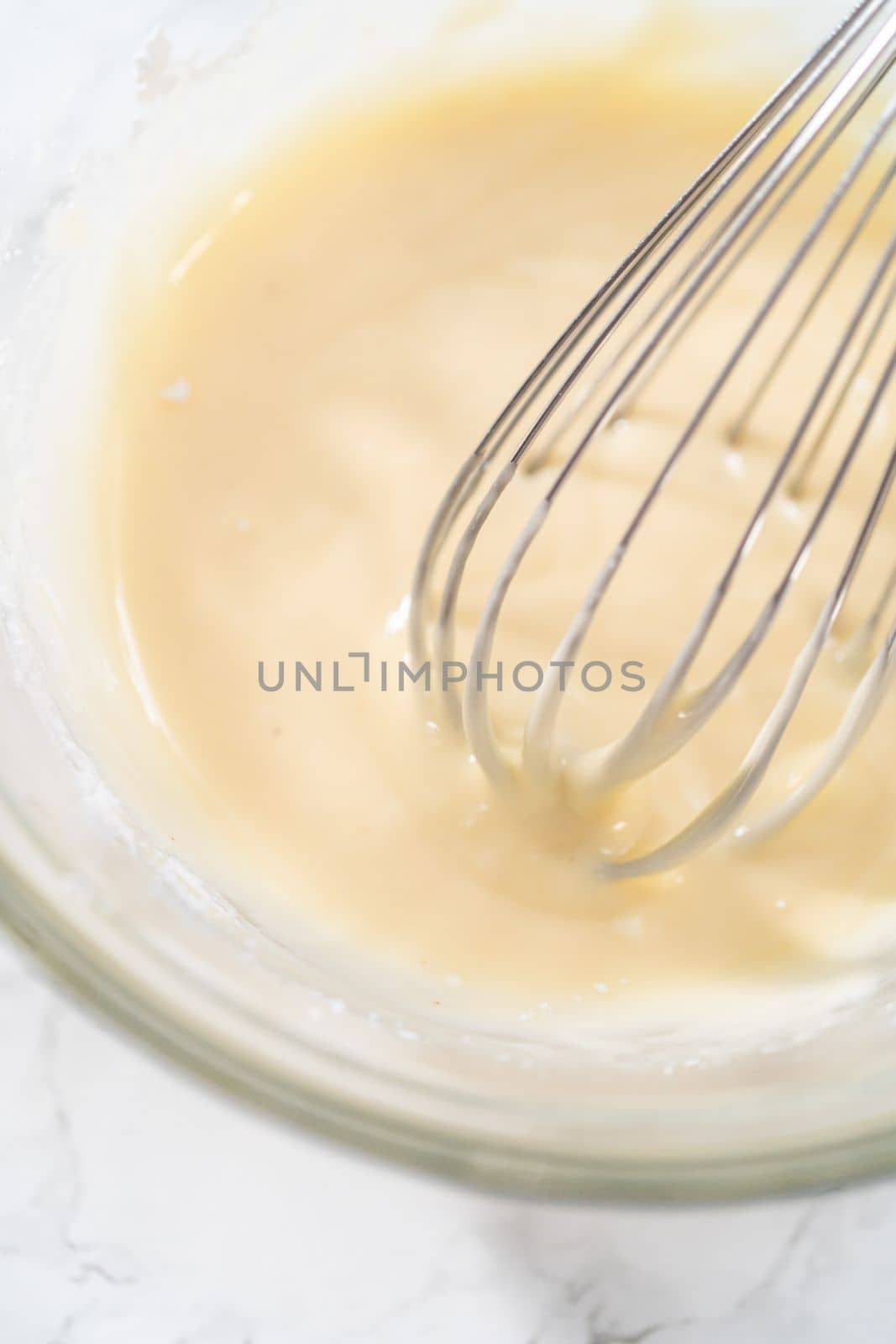 Mixing ingredients with a hand whisk to make eggnog glaze.