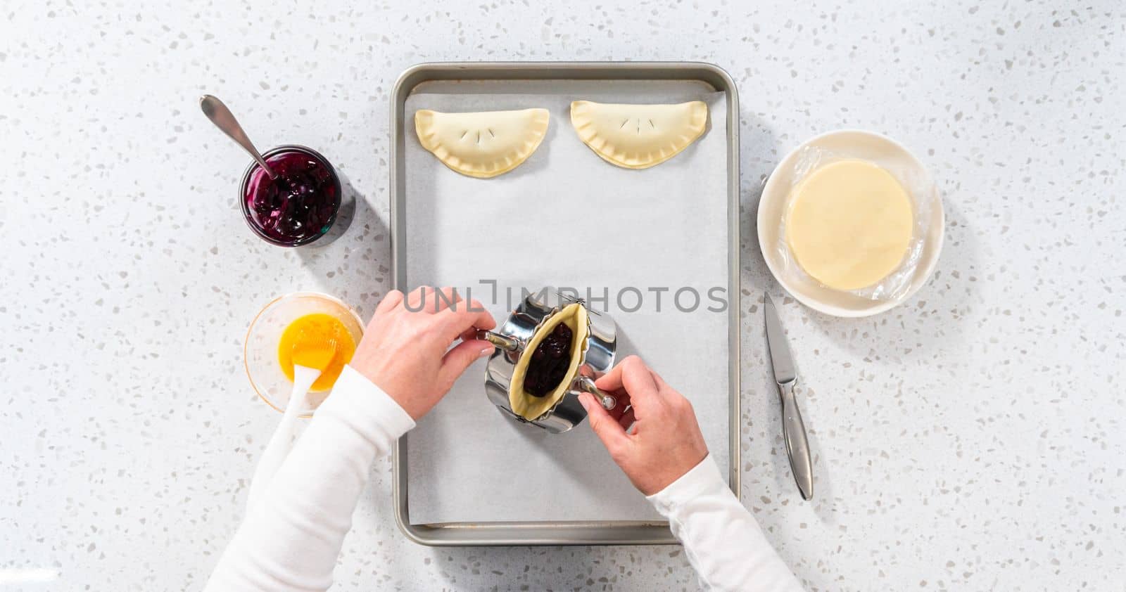 Flat lay. Filling empanada dough with blueberry pie filling to make sweet empanadas with blueberries.