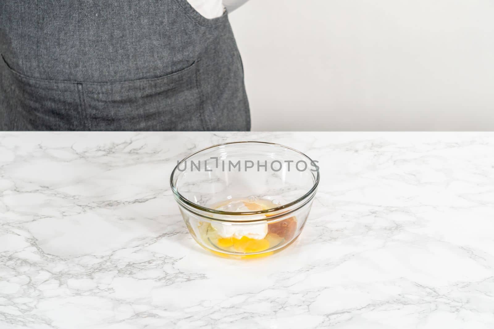 Mixing wet ingredients in a small glass mixing bowl to bake mini vanilla cupcakes with ombre pink buttercream frosting.