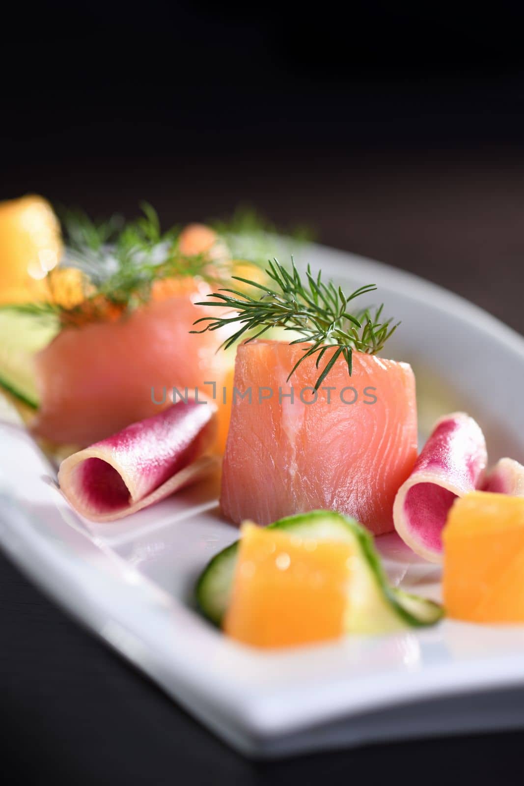  Buffet serving of pickled salmon slices with radish, cucumber and orange cubes