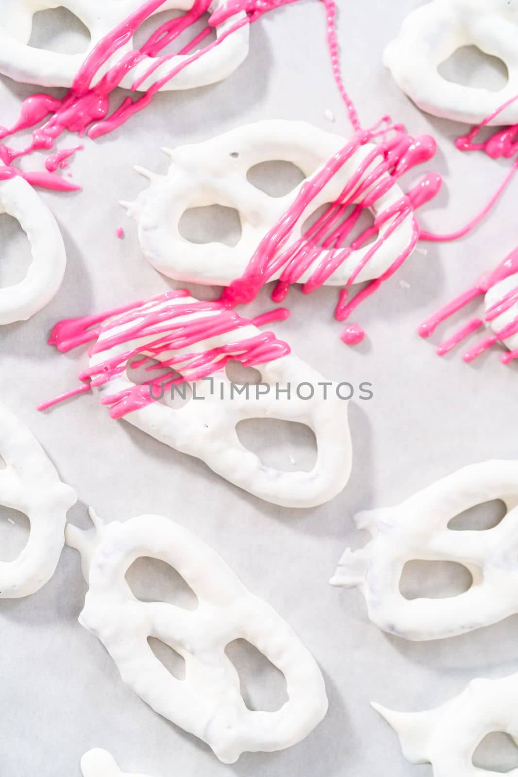 Drizzling melted chocolate over chocolate-dipped pretzels twists.