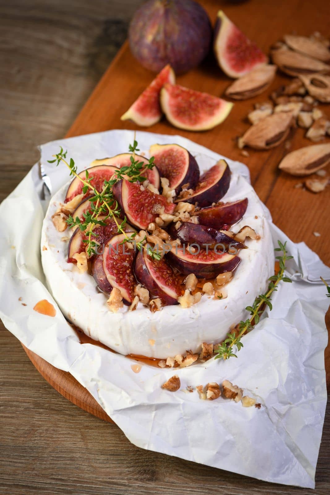 Brie cheese served on a wooden board with figs, walnuts and honey