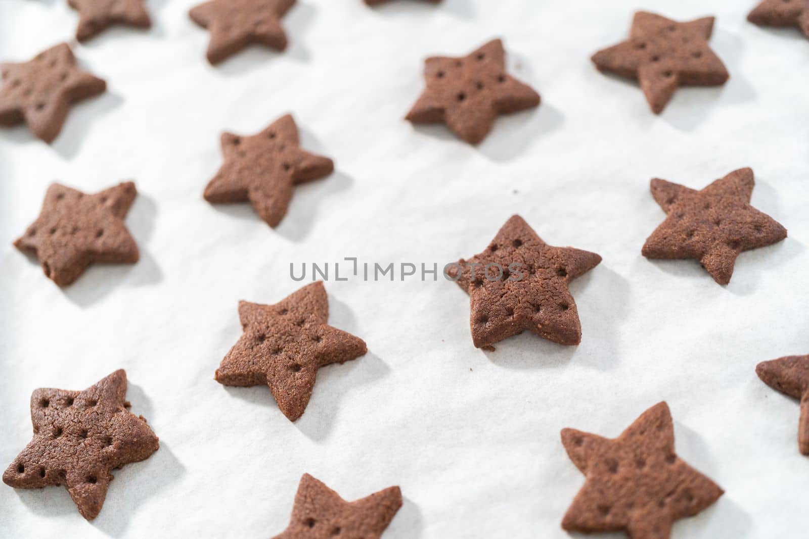 Cooling freshly star-shaped baked chocolate graham crackers on the baking sheet lined with parchment paper.