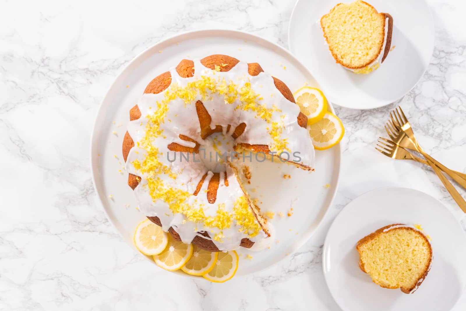 Flat lay. Sliced lemon bundt cake decorated with lemon zest on a cake stand.
