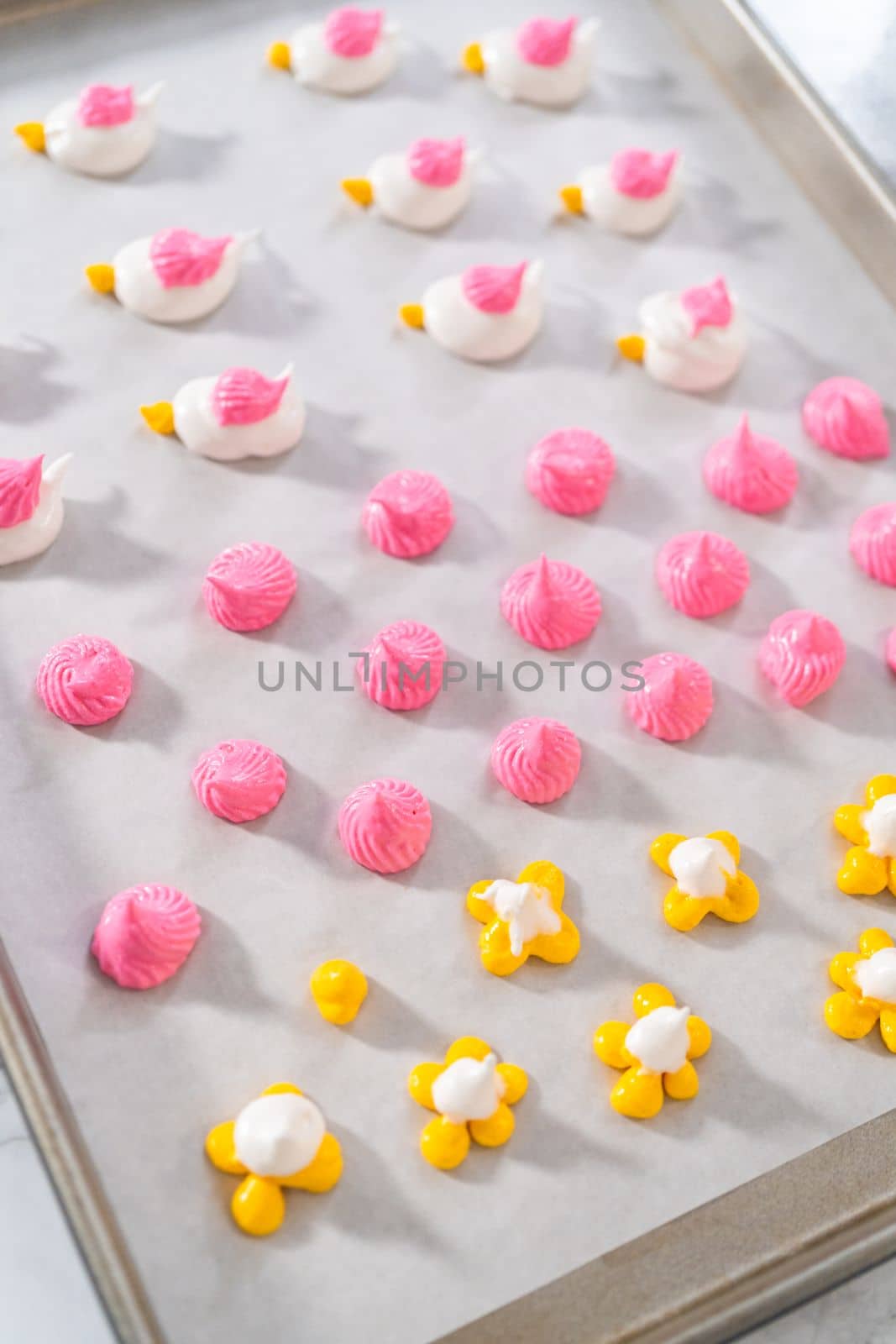 Piping meringue with piping bags into the baking sheet lined with parchment paper to bake Easter meringue cookies.