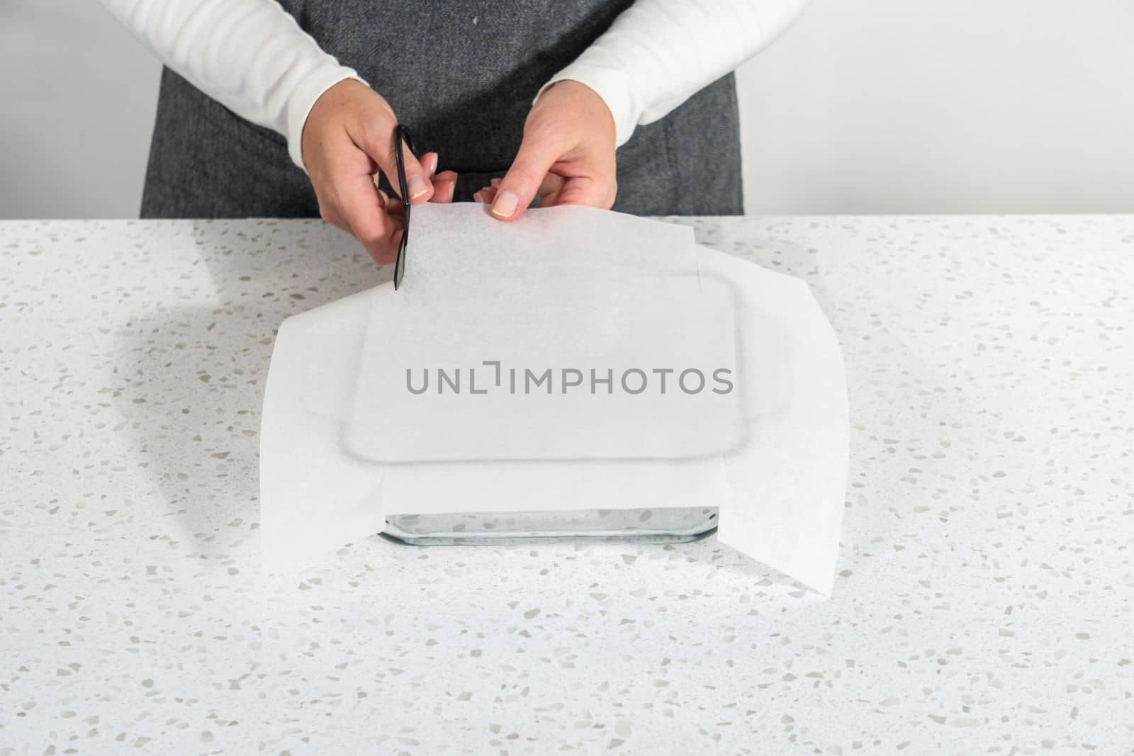 Lining glass baking pan with parchment paper sheet to prepare plain fudge.
