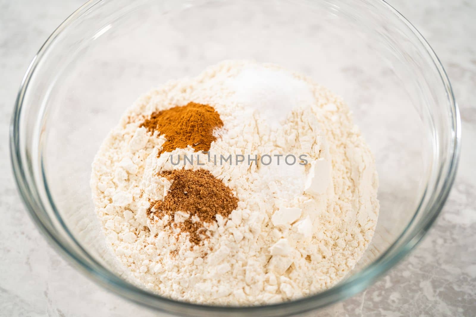 Mixing ingredients in a large glass mixing bowl to bake eggnog scones.