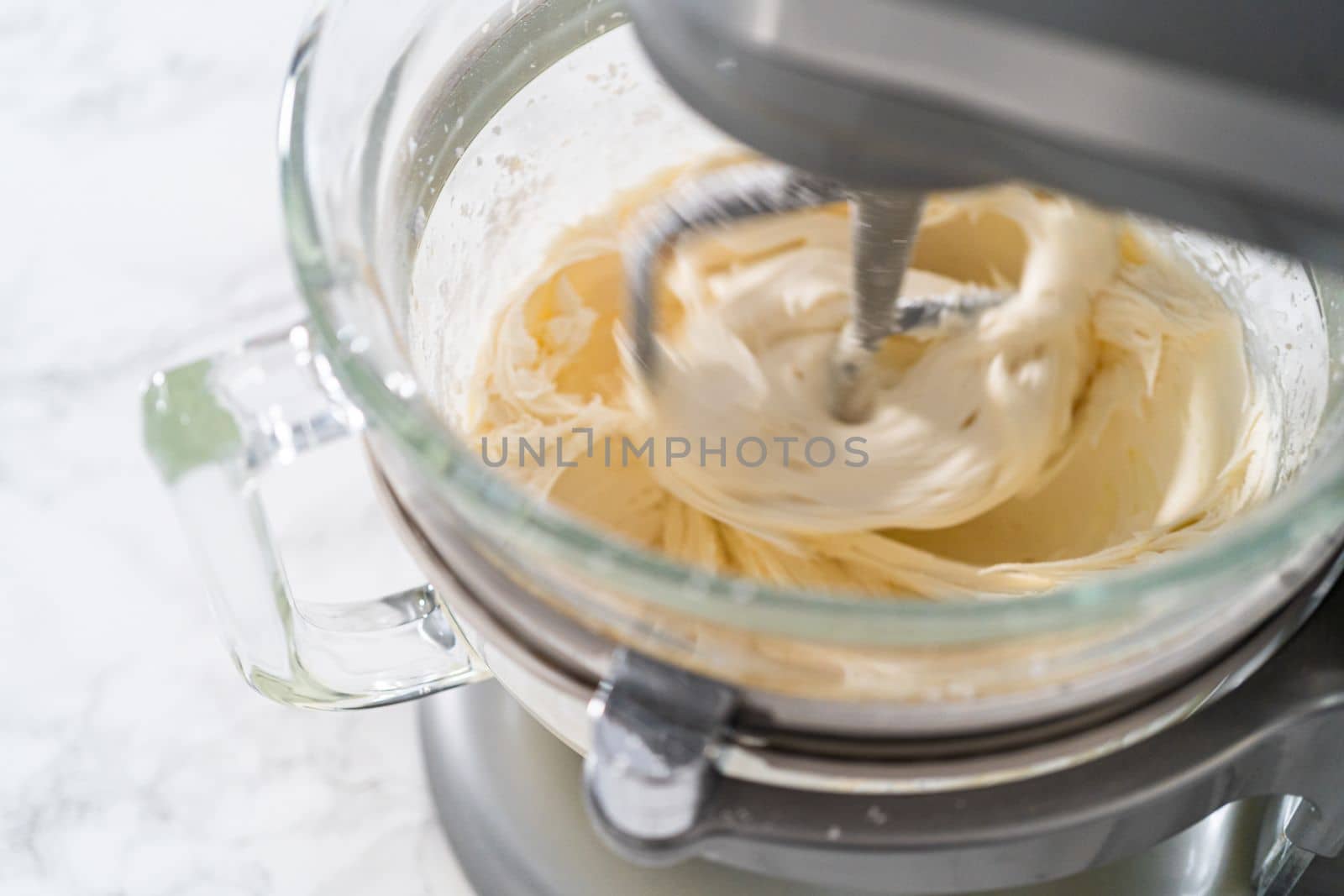 Mixing ingredients in kitchen electric mixer to make ombre pink buttercream frosting.