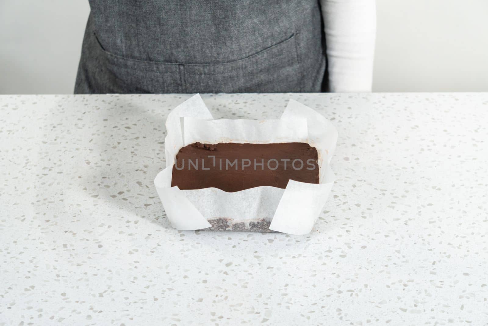 Cutting plain homemade fudge into small pieces on a white cutting board.