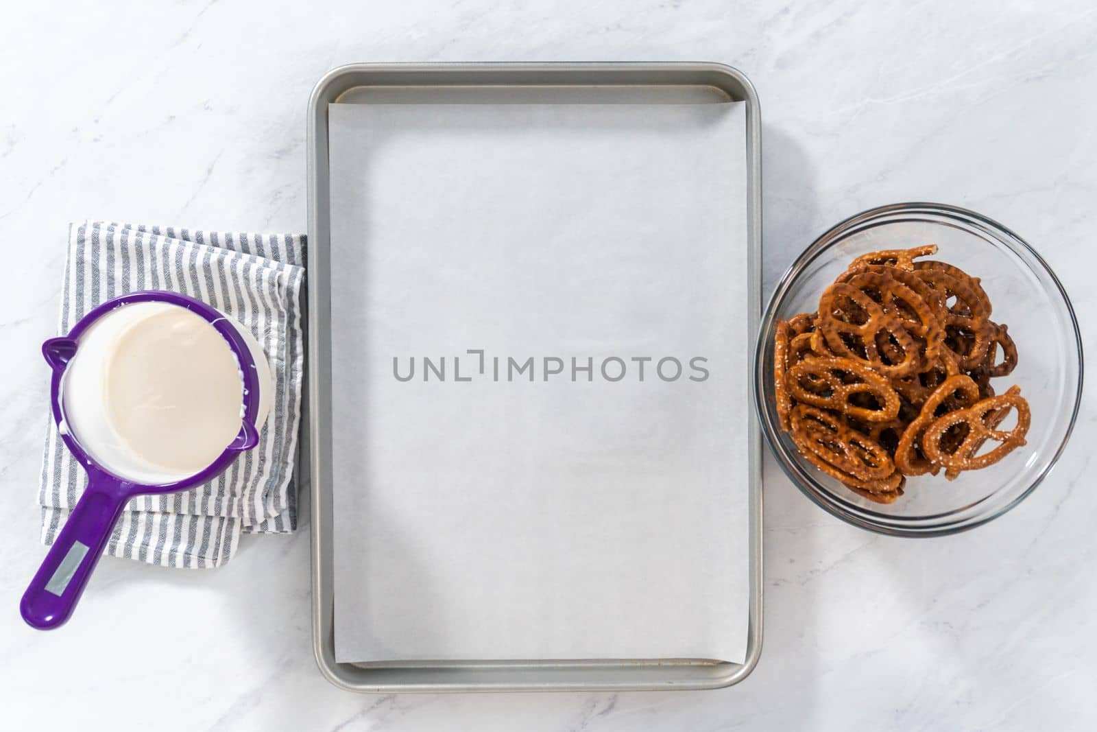 Flat lay. Dipping pretzels twists into melted chocolate to make chocolate-covered pretzel twists.