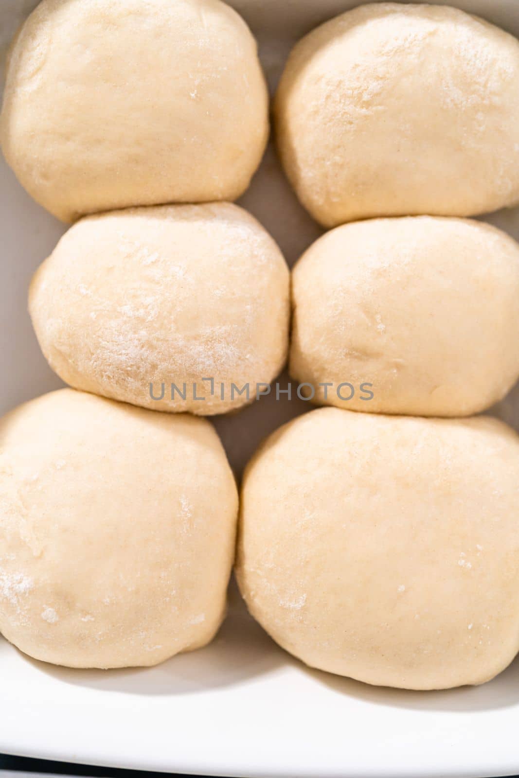 Rising dough in a white ceramic dish to prepare dinner rolls.