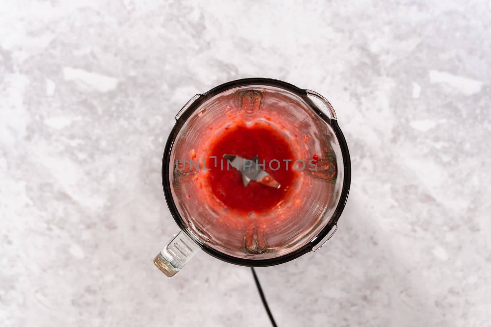 Flat lay. Blending fresh strawberries in a kitchen blender to prepare the strawberry buttercream frosting.