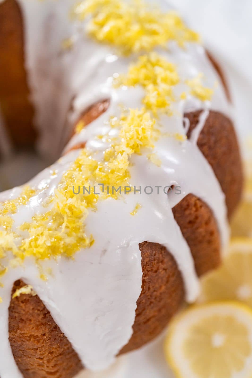 Lemon bundt cake decorated with lemon zest on a cake stand.