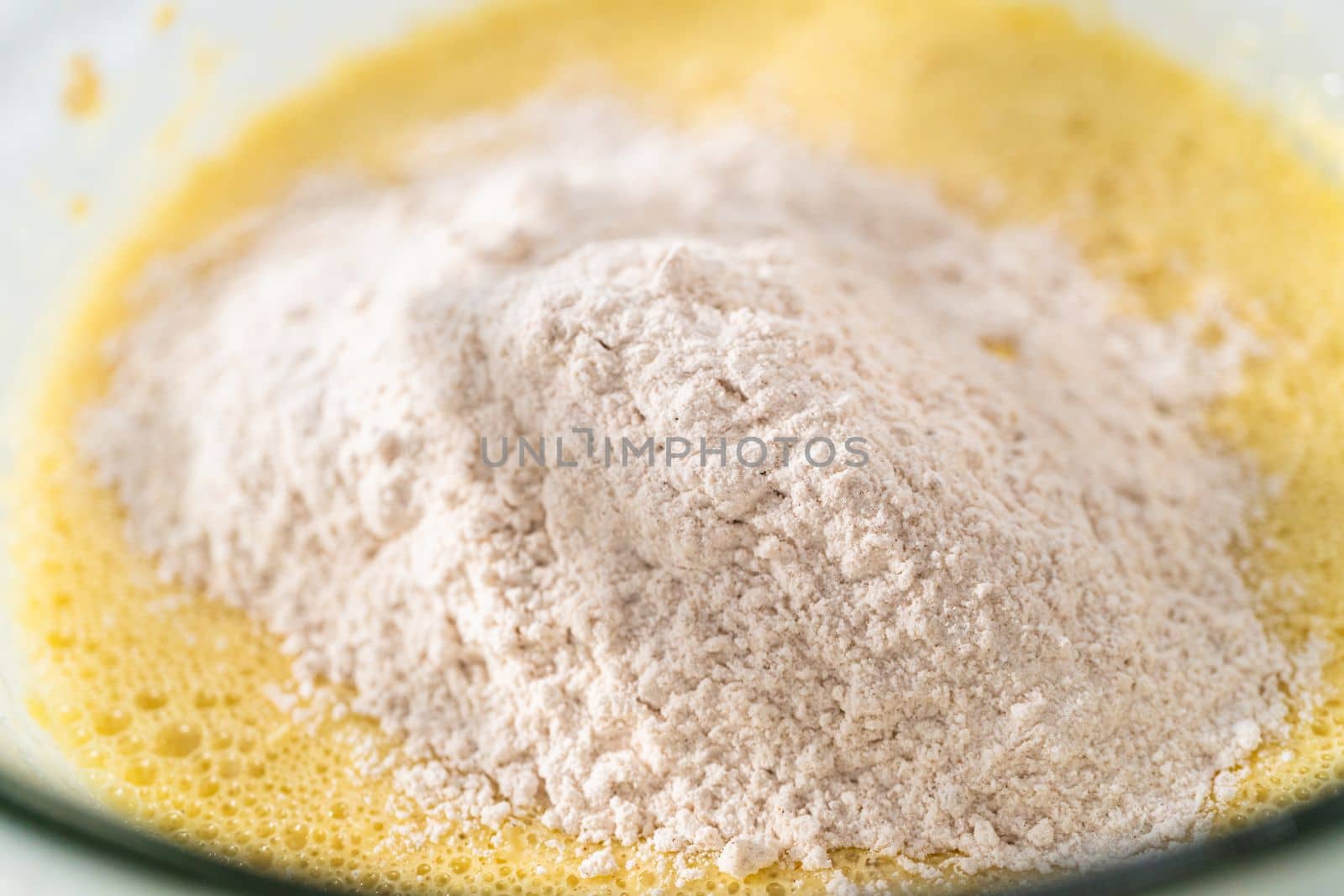 Mixing ingredients with a hand mixer in a large mixing bowl to bake eggnog bundt cake.