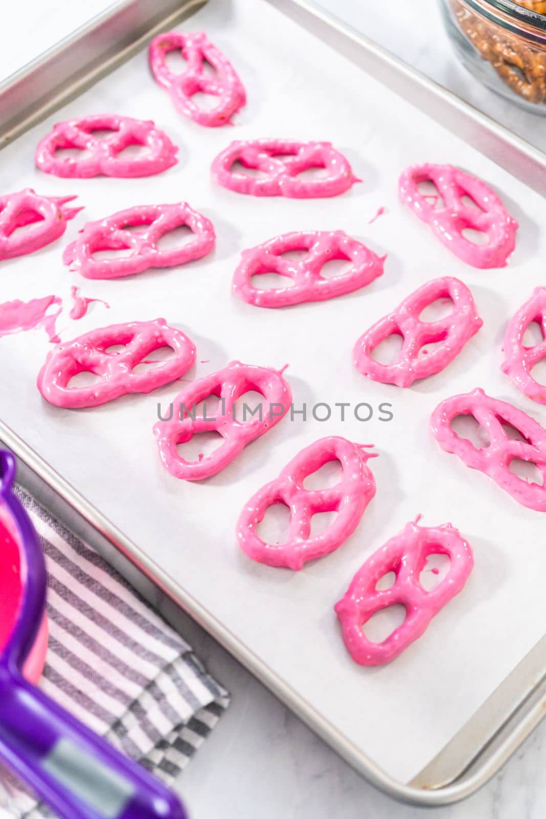 Dipping pretzels twists into melted chocolate to make chocolate-covered pretzel twists.