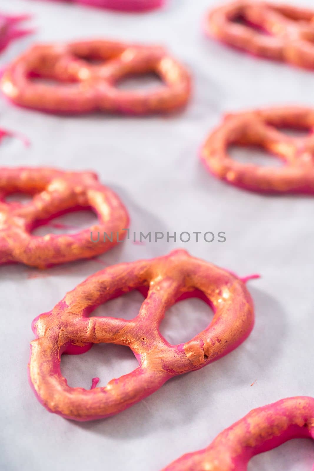 Painting chocolate-covered pretzel twists with glittery luster.
