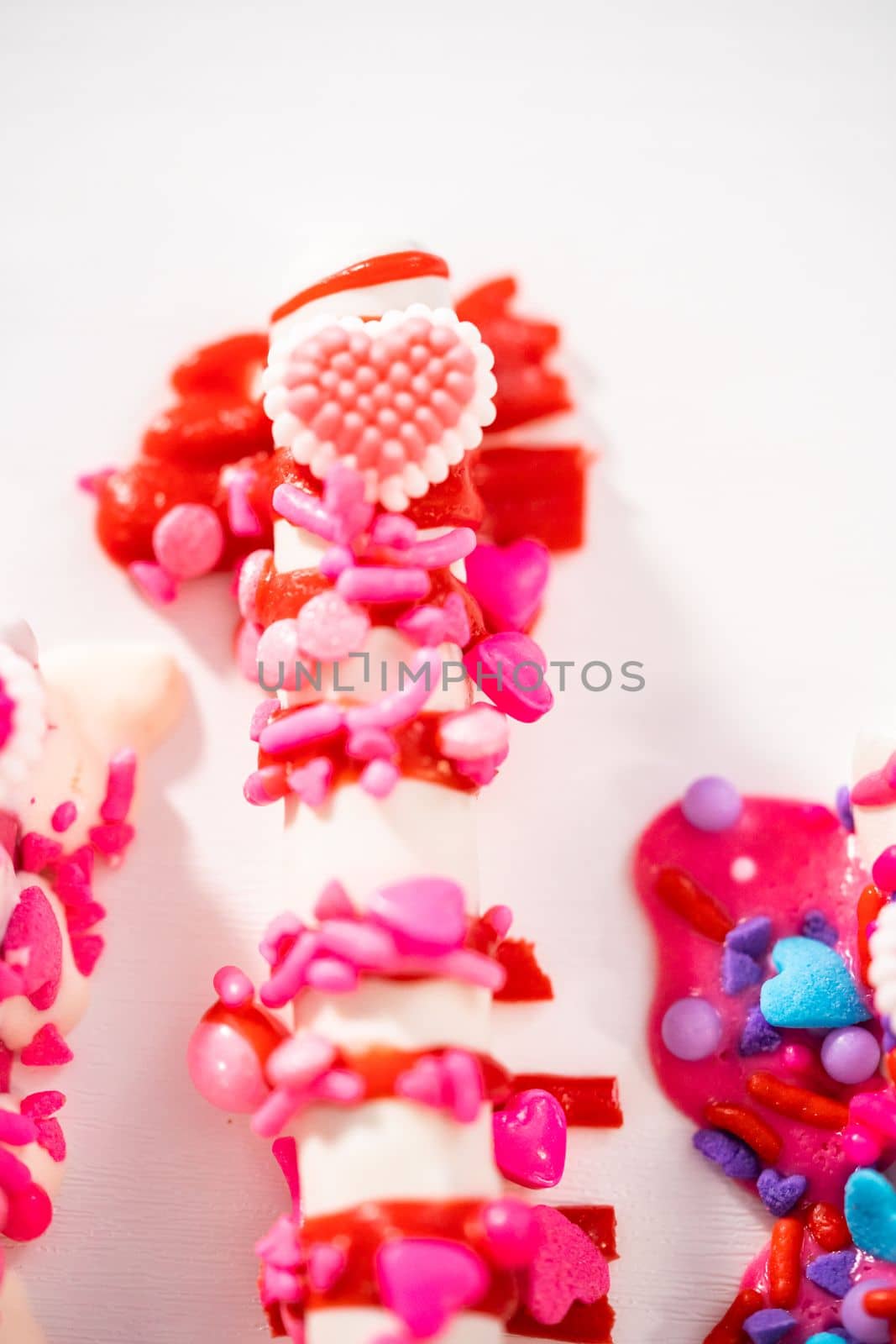 Chocolate-covered pretzel rods decorated with heart-shaped sprinkles for Valentine's Day.