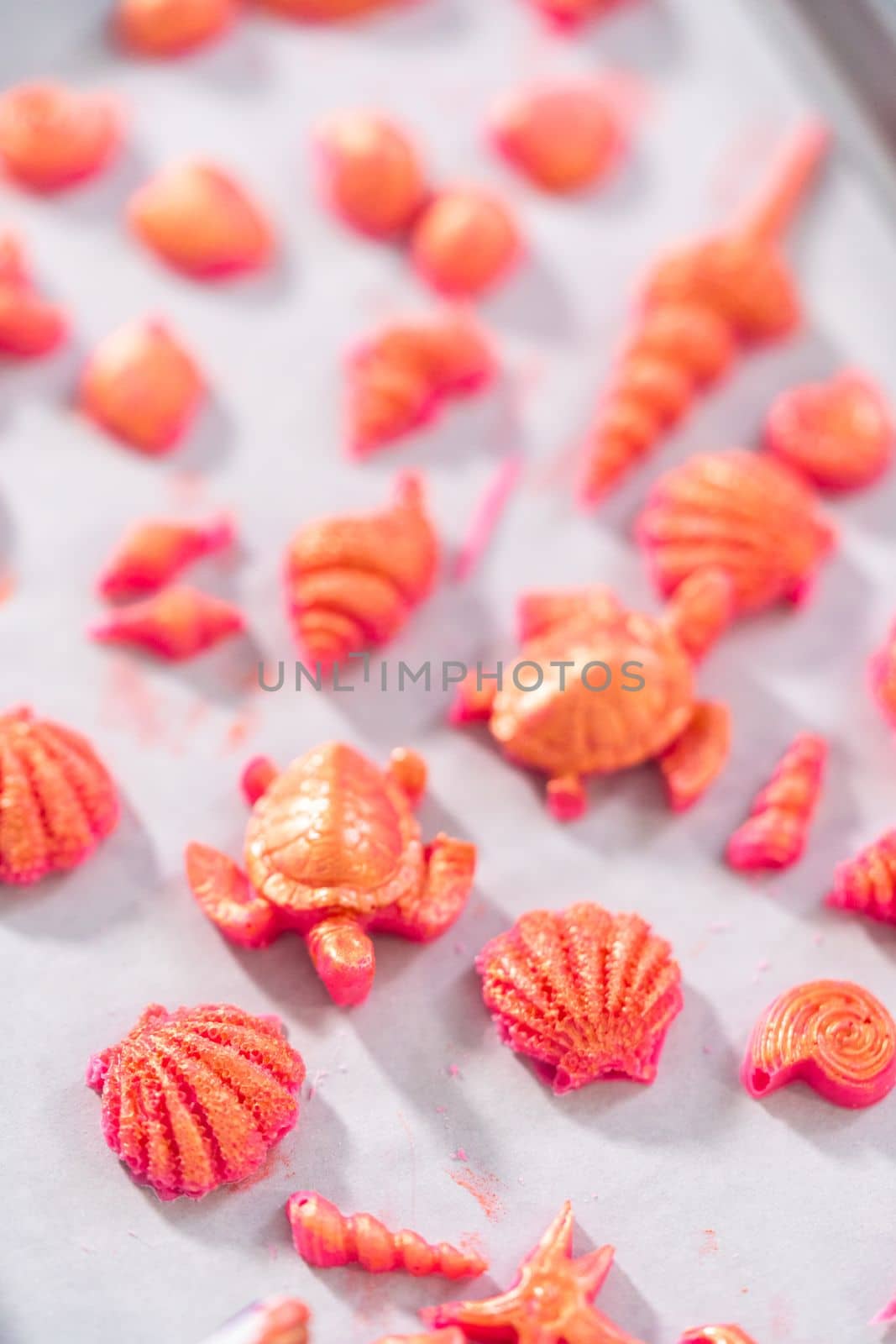Painting sea-shaped chocolates with glittery luster to decorate chocolate-dipped pretzels twists.