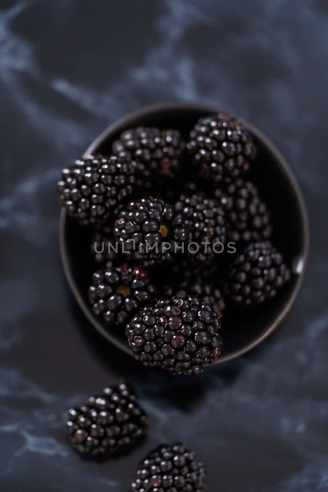 Fresh organic blackberries on ablack marble surface.