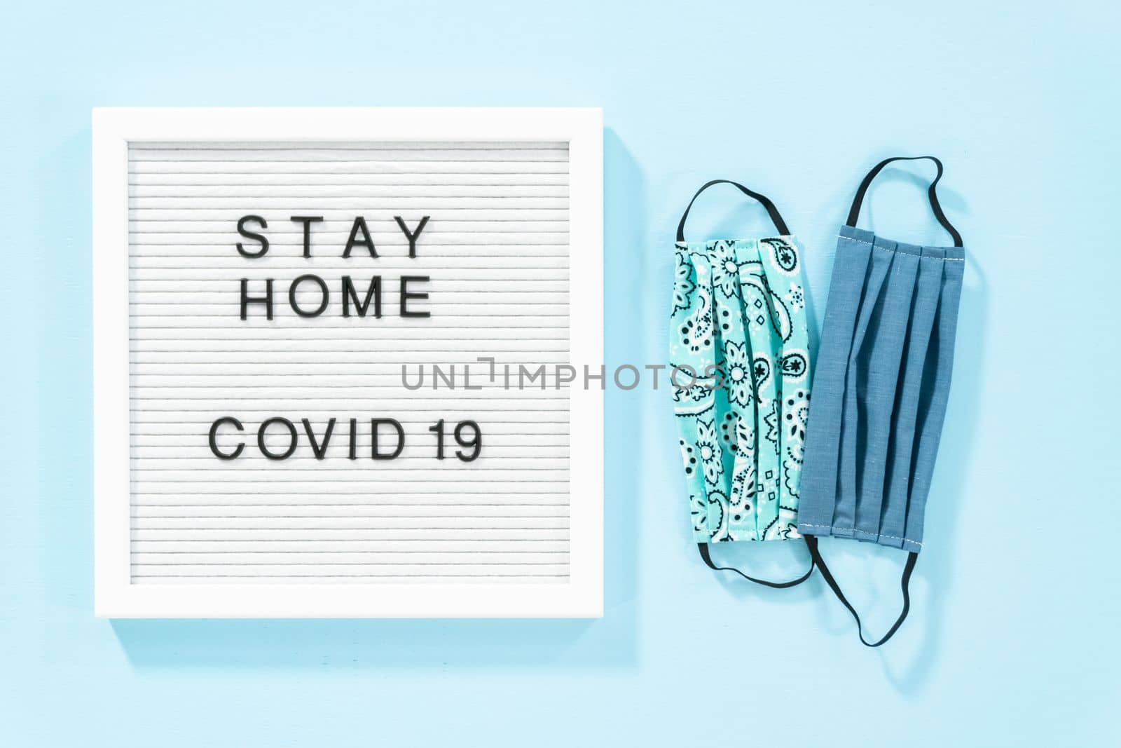 STAY HOME and COVID-19 sign on message board with a homemade face mask.