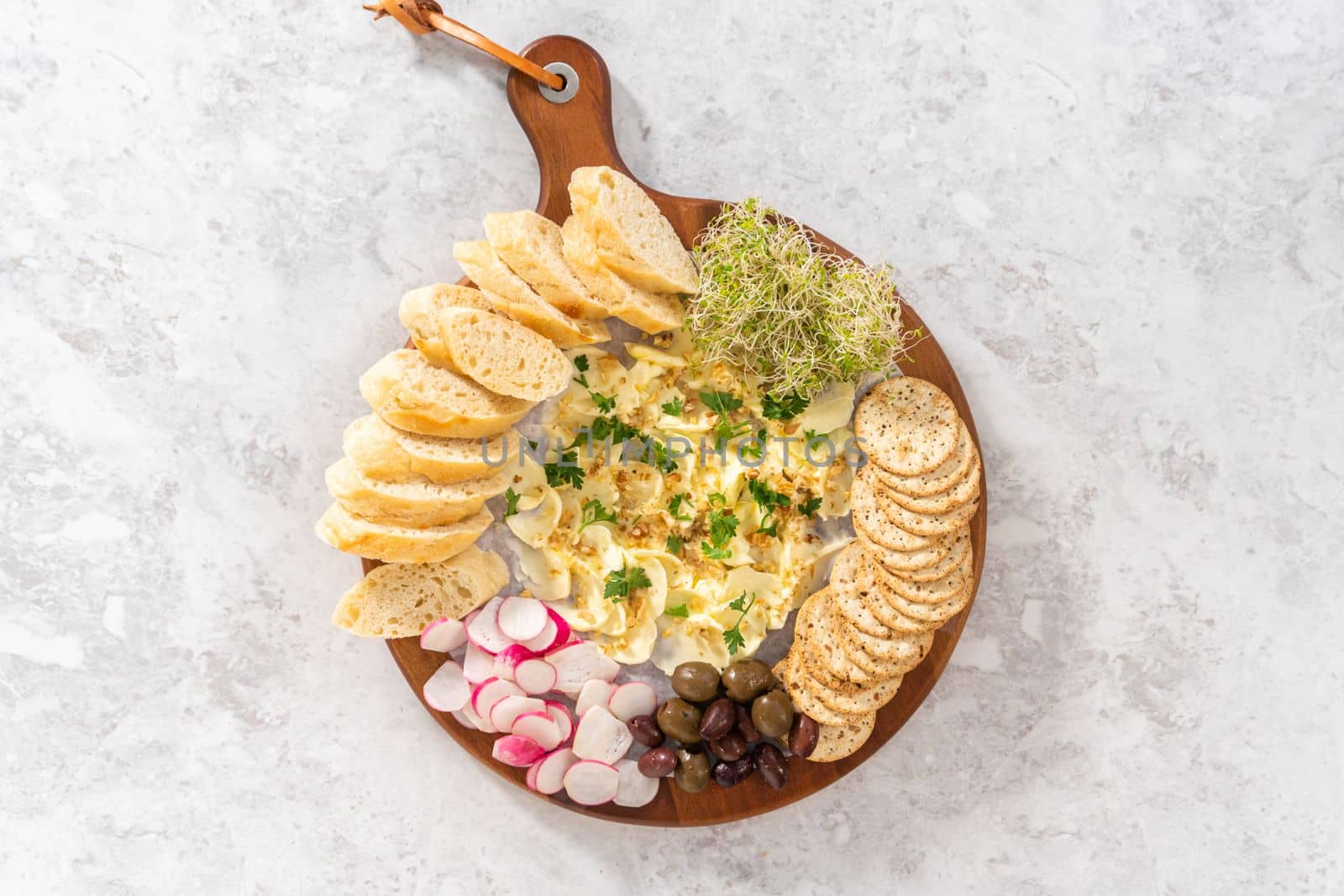 Flat lay. Butter board with vegetables and bread on a round wood cutting board.