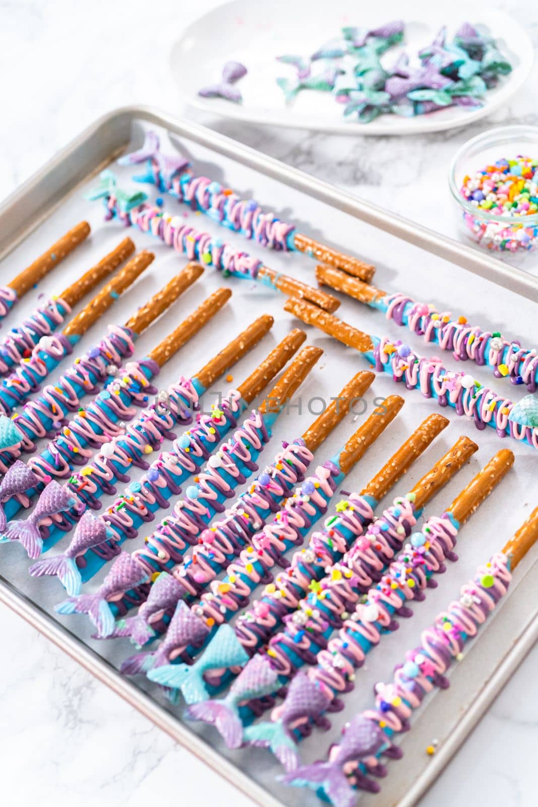 Mermaid chocolate pretzel rods drizzled with pink and purple chocolate and covered with sprinkles.