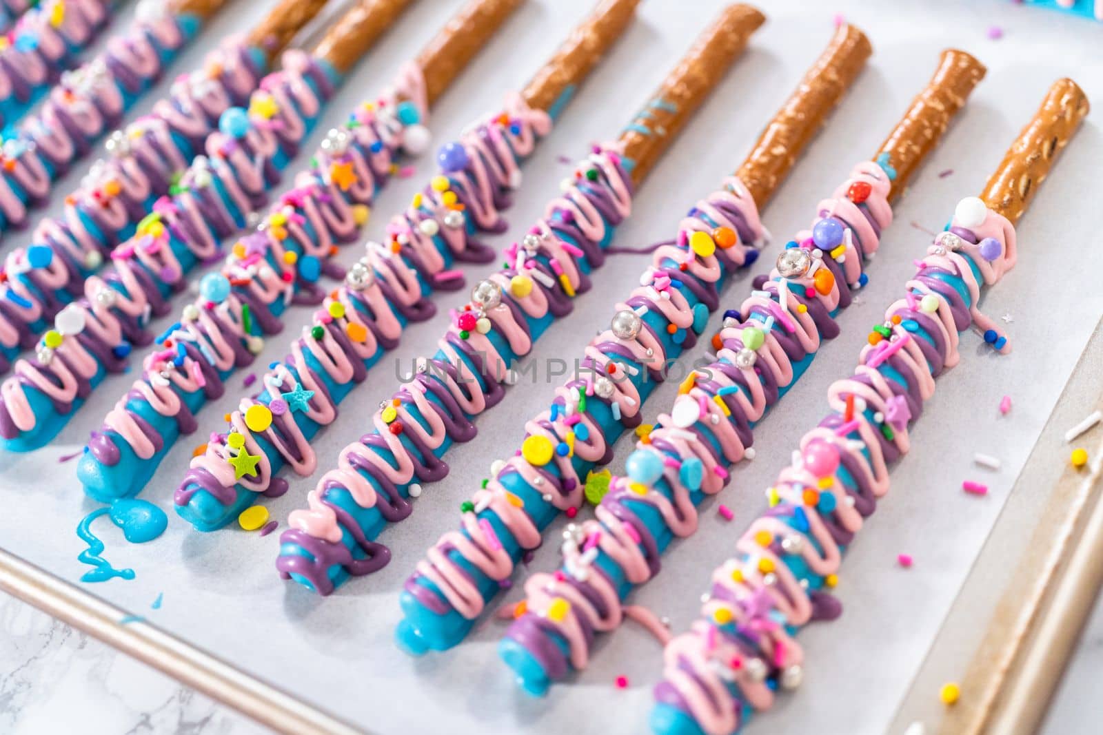 Mermaid chocolate pretzel rods drizzled with pink and purple chocolate and covered with sprinkles.