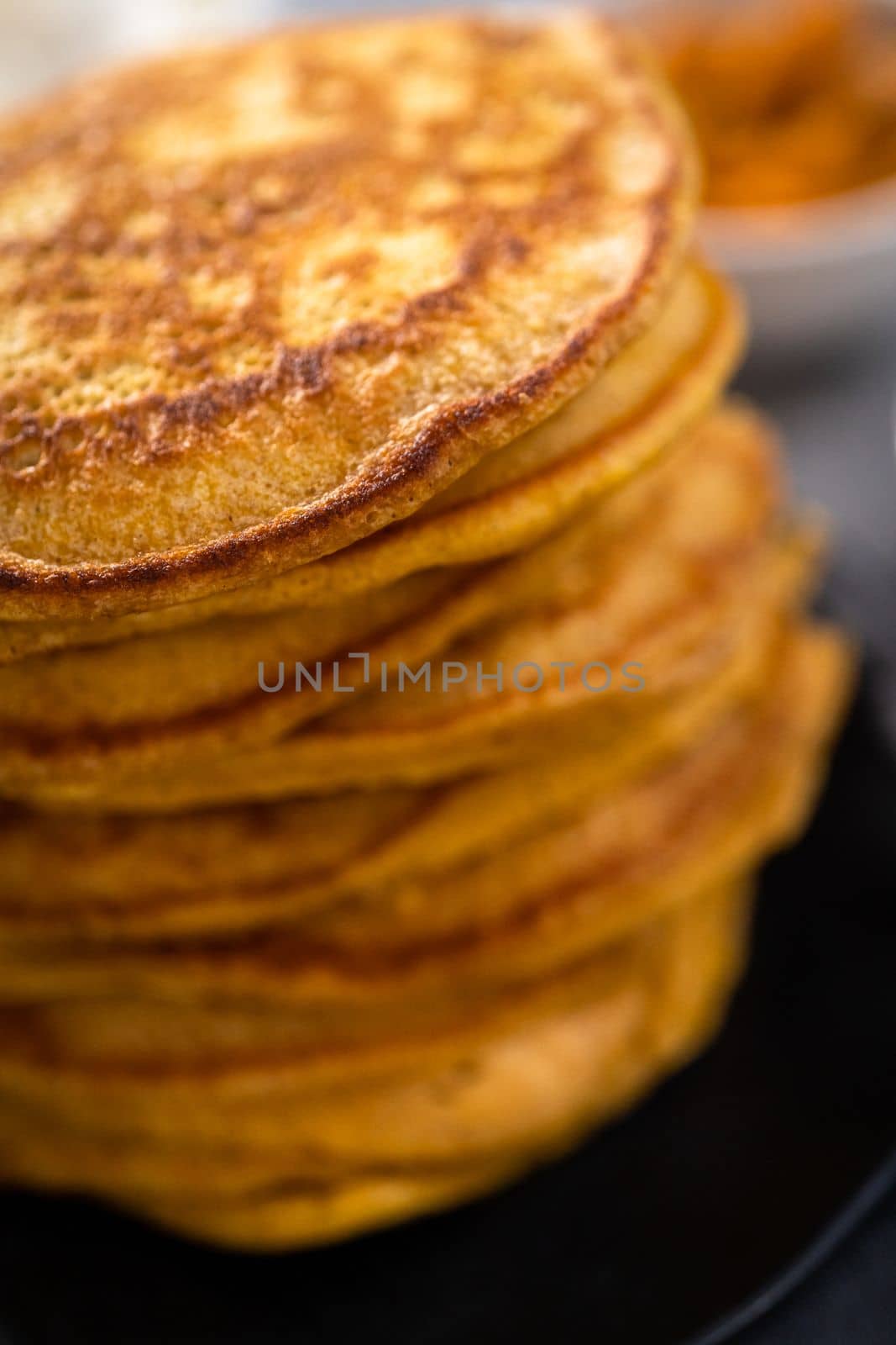 Stack of fresh pumpkin pancakes on a black plate.