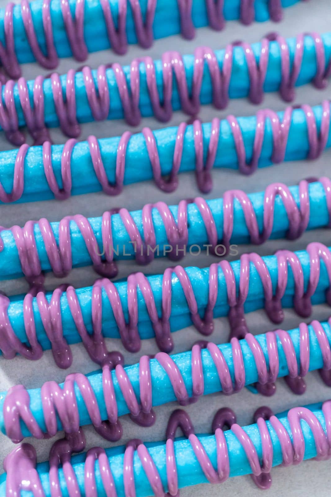 Drizzled with chocolate pretzel rods drying on a baking sheet lined with parchment paper.