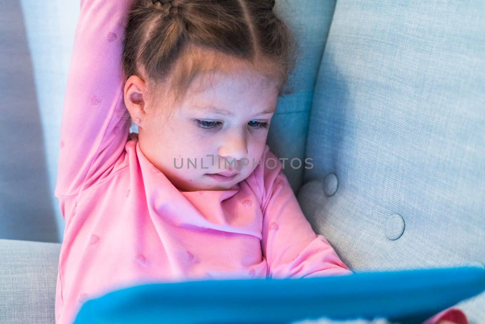 Little girl reading books on her tablet at homeschool.