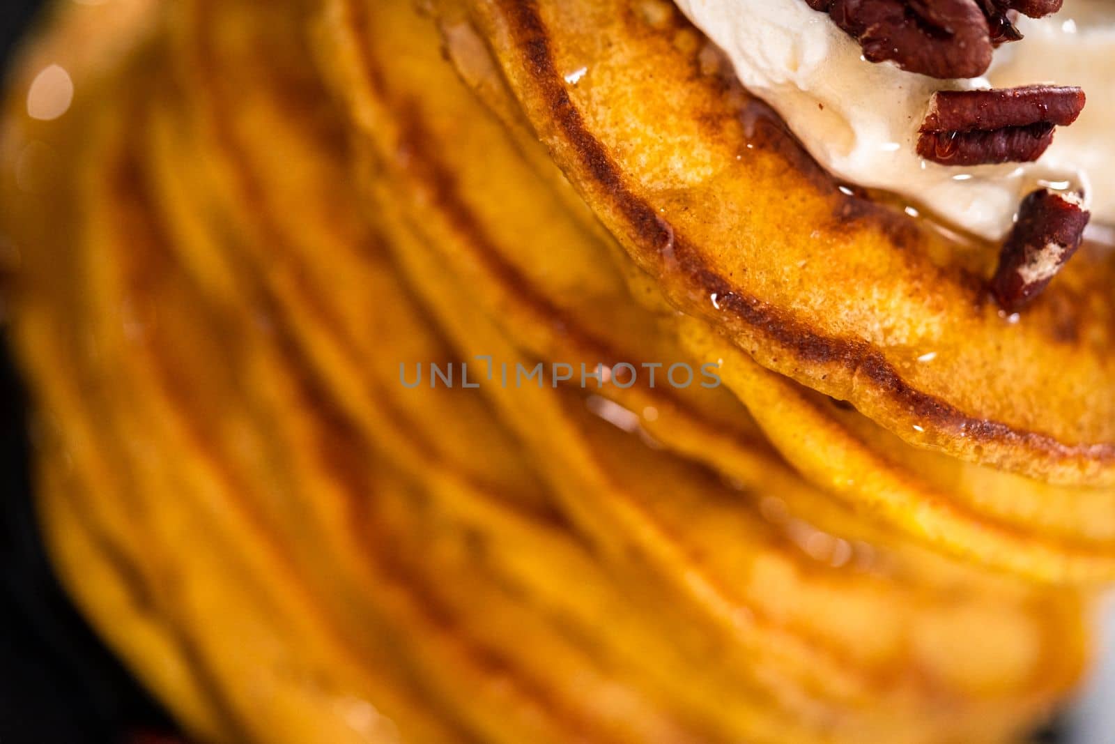 Stack of fresh pumpkin pancakes on a black plate.