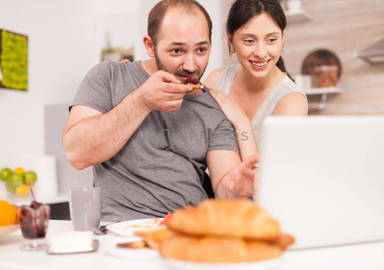 Young family receiving good news on email in the morning eating breakfast. Successful overjoyed euphoric entrepreneur at home in the morning, winner and business triumph