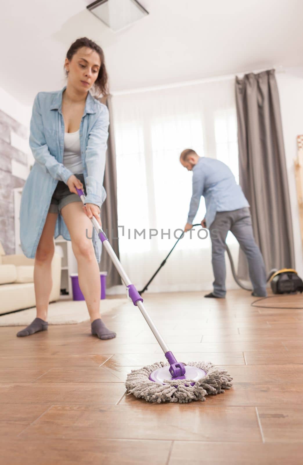 Woman wiping floor with mop in apartment.