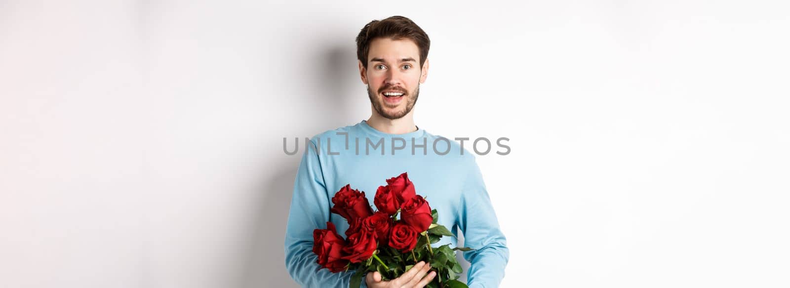 Romantic boyfriend bring beautiful bouquet of red roses on valentines day, having date with girlfriend, saying I love you, standing passionate on white background by Benzoix