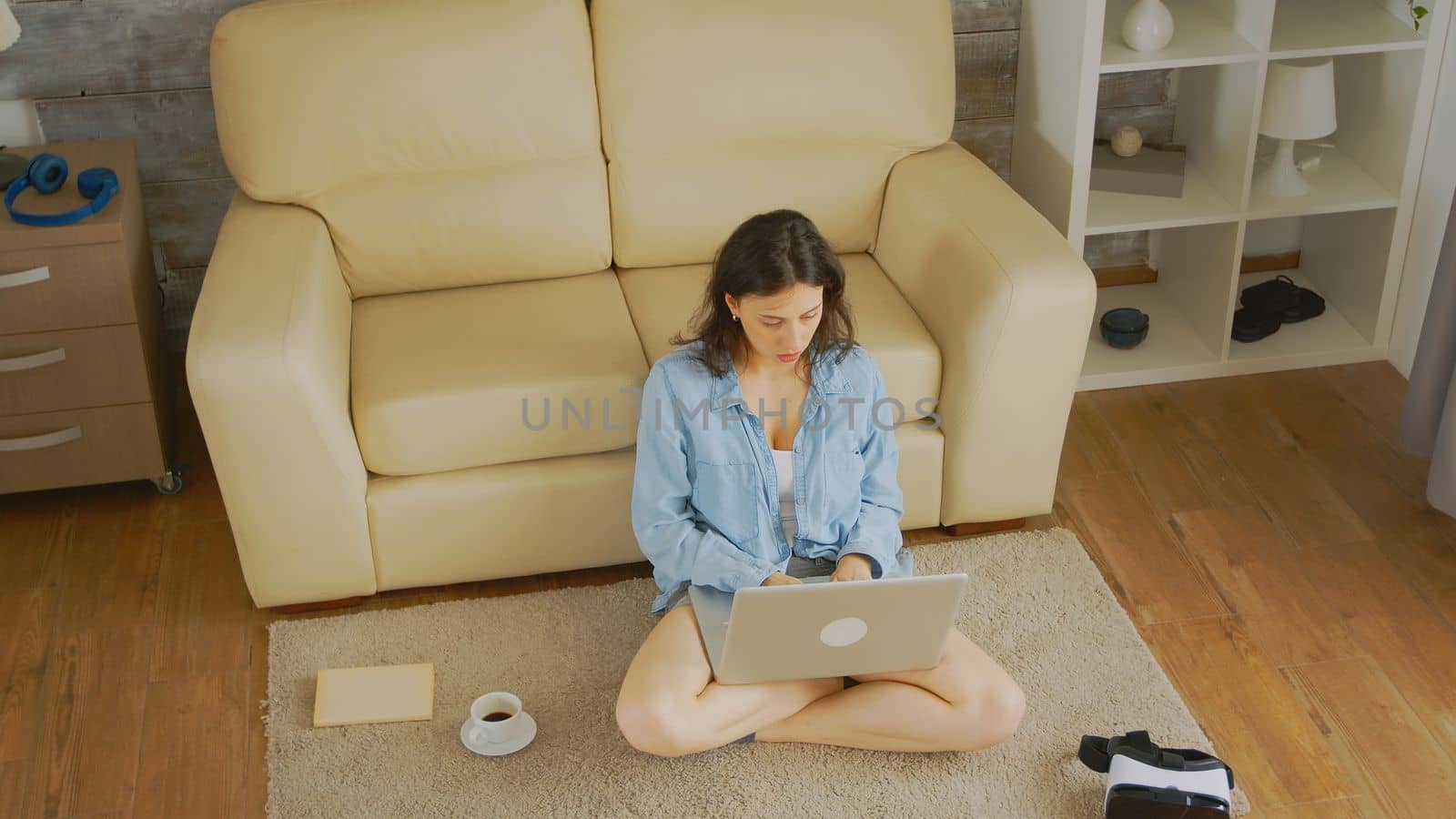 Top down view of caucasian woman typing an email sitting on the floor of her cozy bright home